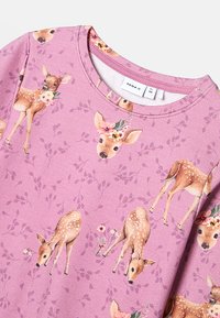 Różowa koszula z długim rękawem z powtarzającym się wzorem jeleni z kwiatowymi akcentami. Miękka tkanina z okrągłym dekoltem i gładką fakturą.