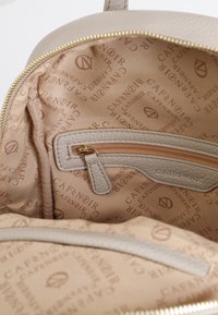 Interiér tan hnědé kožené tašky s béžovou podšívkou s embosovaným logem "Café Noir", zipovou kapsou a hladkým texturovaným materiálem.