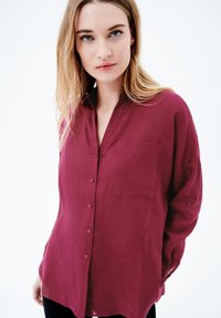 Camicia abbottonata bordeaux realizzata in tessuto leggero, con taschino, vestibilità comoda, colletto e maniche lunghe.