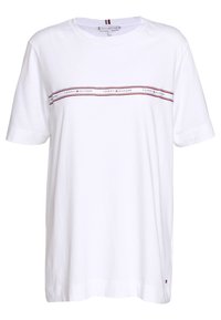 Bílé bavlněné tričko s kulatým výstřihem, krátkými rukávy a horizontálními červenými a námořnickými pruhy, na kterých je napsáno "TOMMY HILFIGER" přes hrudník.