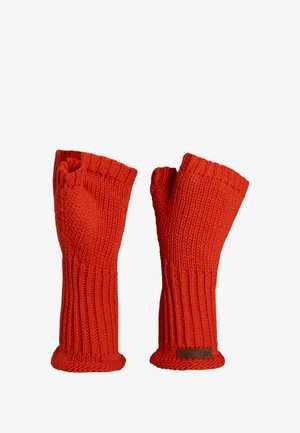 Czerwone dzianinowe rękawiczki bez palców z prążkowanym wzorem, otwartymi końcówkami palców i mankietami na nadgarstki. Posiadają małą brązową metkę na jednej rękawiczce.