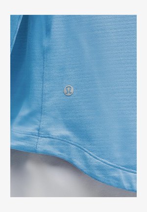 Svetlomodré športové tričko s textúrovanou látkou, jemnými horizontálnymi pruhmi a strieborným logom v blízkosti lemu.