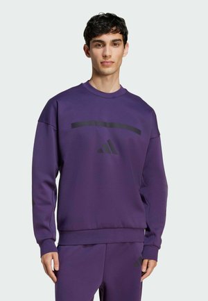 Purple sweatshirt made of soft fabric, featuring a black horizontal stripe and an Adidas logo. Crew neck design with ribbed cuffs.