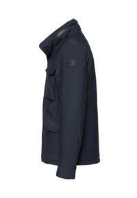 Chaqueta impermeable de color azul marino con un cuello alto, tres bolsillos frontales y un logotipo sutil en el hombro. Textura lisa y mate.