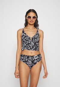 Juodas gėlių bikinis, sudarytas iš sutrumpinto viršaus su raiščiu ir atitinkamų aukštai liemeniui dugnų, abu su baltais lapų raštais.