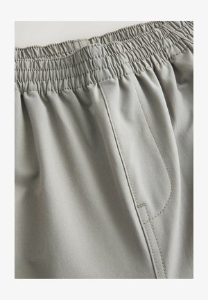 Heledad hallid lühikesed püksid, millel on elastne vöökoht, sile tekstuur ja küljeõmbluse detail. Kujundatud mugavuseks ja lihtsaks selga panekuks.