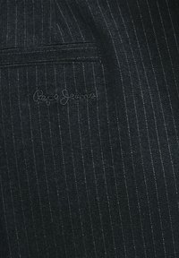 Tissu en denim foncé avec des rayures verticales fines, présentant un logo "Pepe Jeans" brodé. Comprend un petit détail de poche.