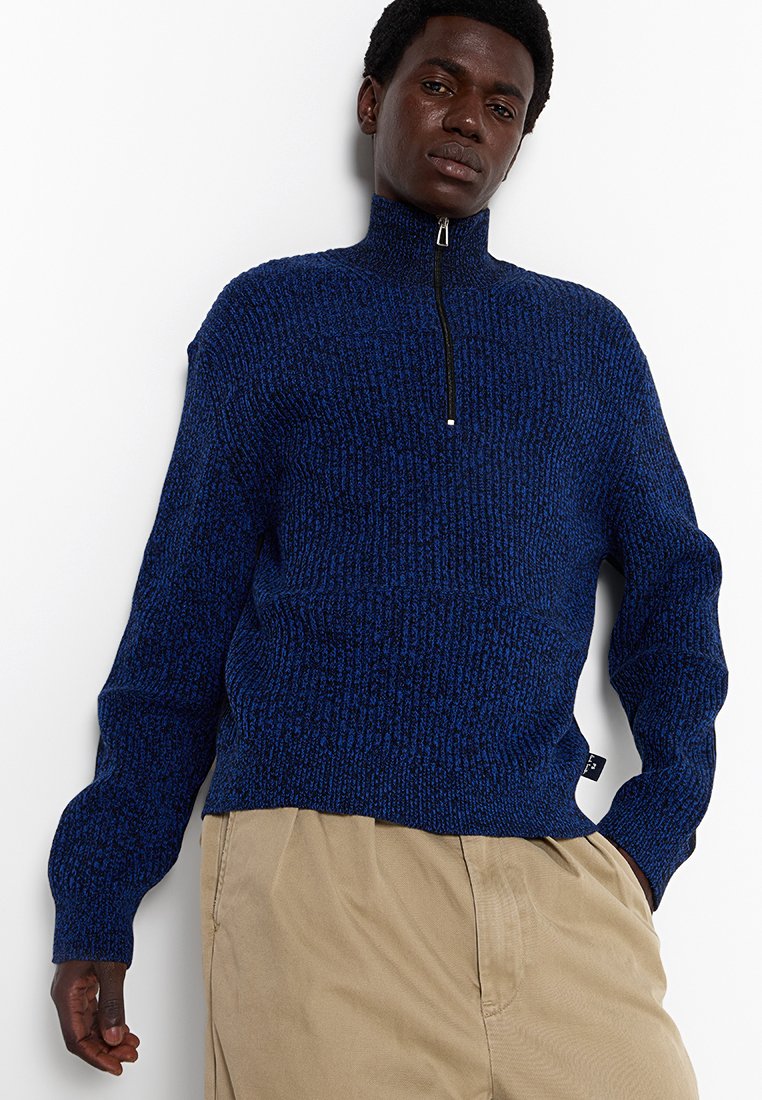 Navyblauer Strickpullover mit hohem Kragen, einem Viertel-Reißverschluss und strukturiertem Muster. Verfügt über lange Ärmel und gerippte Saumakzente.