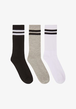 Trzy pary skarpetek załogowych w kolorach czarnym, szarym i białym. Każda skarpetka ma prążkowaną teksturę oraz dwa poziome czarne paski u góry.
