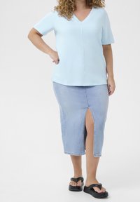 Lyseblå kortærmet V-hals top kombineret med en lyseblå denim knælang nederdel med en sidesprede og sorte platform sandaler.