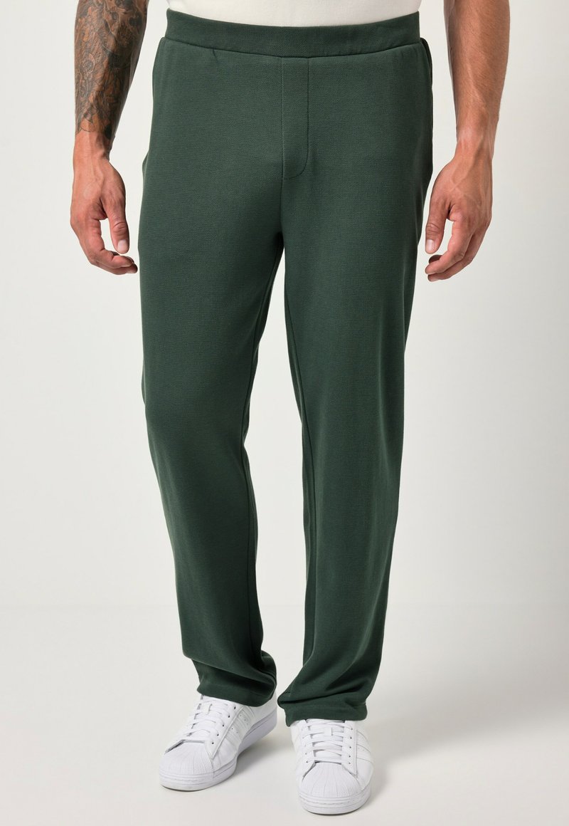 Pantaloni sportivi verdi in un tessuto morbido e testurizzato, con una vestibilità rilassata e vita elastica, abbinati a sneaker bianche. Nessun motivo visibile.