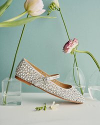 Srebrne baleriny pokryte okrągłymi rhinestonami, z paskiem na klamrze. Płaska, drewniana podeszwa, jasne wnętrze i gładka tekstura.