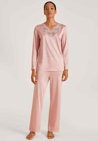 Lange mouwen, V-hals pyjamapakket in zachtroze stof. Kenmerkt kantafwerking op de halslijn en broekzoom, met een relaxte pasvorm en een gladde textuur.