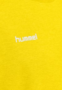 Geel katoenen t-shirt met een witte "hummel" logo op de voorkant. De stof heeft een gladde textuur met een licht gemêleerd uiterlijk.
