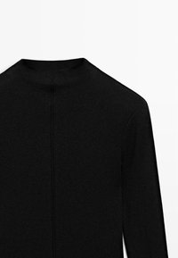 Maglione nero a maglia con collo alto e maniche lunghe. Presenta una cucitura centrale sulla schiena per un tocco di design in più.