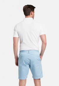 Witte poloshirt en lichtblauwe shorts, katoenen materiaal, casual ontwerp, effen kleuren, achteraanzicht, met een zak op de shorts.