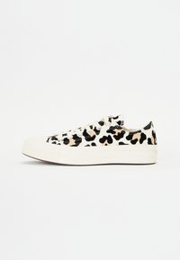Zapatillas de lona blancas con un estampado de leopardo en negro y beige, suela de goma plana y sistema de cordones estándar.