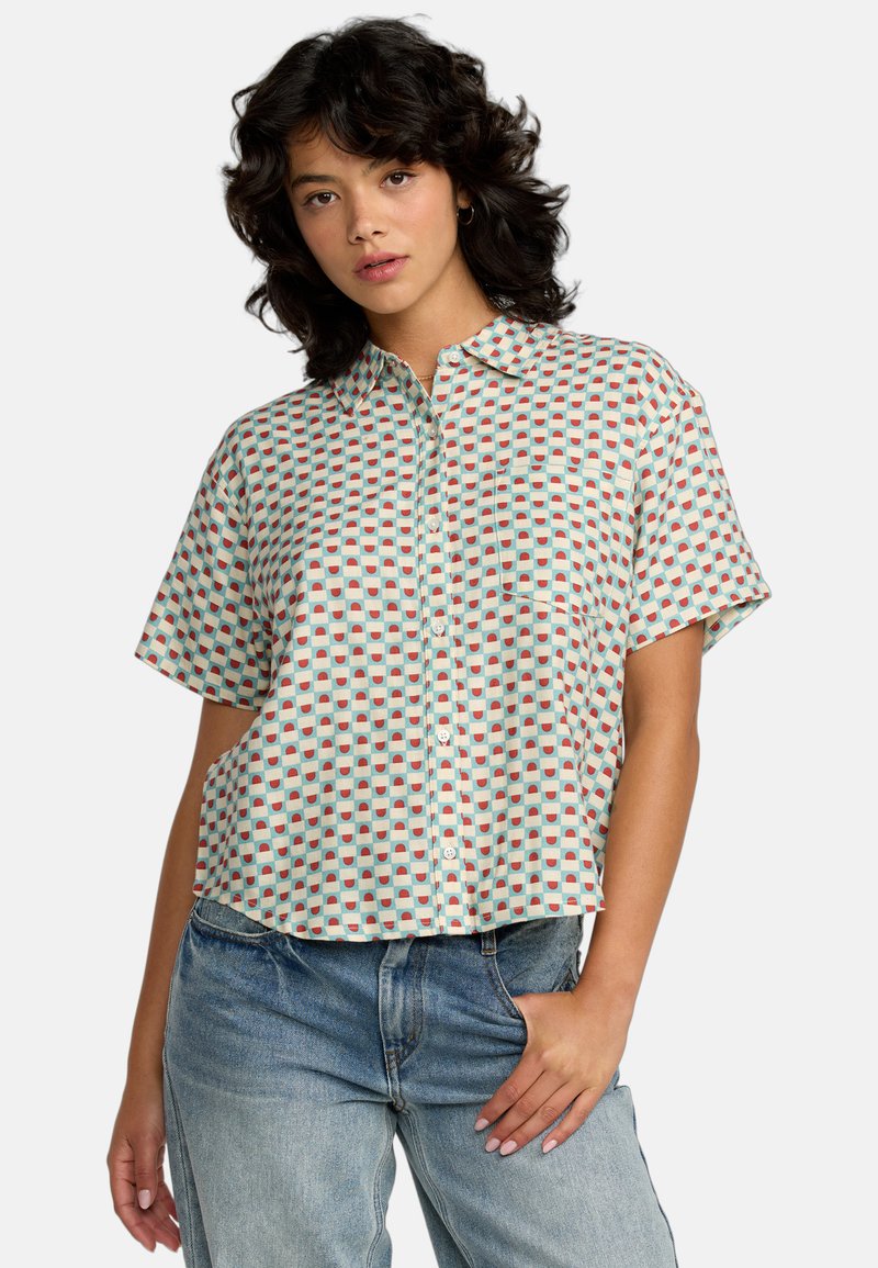 Camisa de manga corta abotonada en azul claro con un patrón geométrico de pequeños cuadrados rojos y azul oscuro. Incluye un único bolsillo en el pecho.