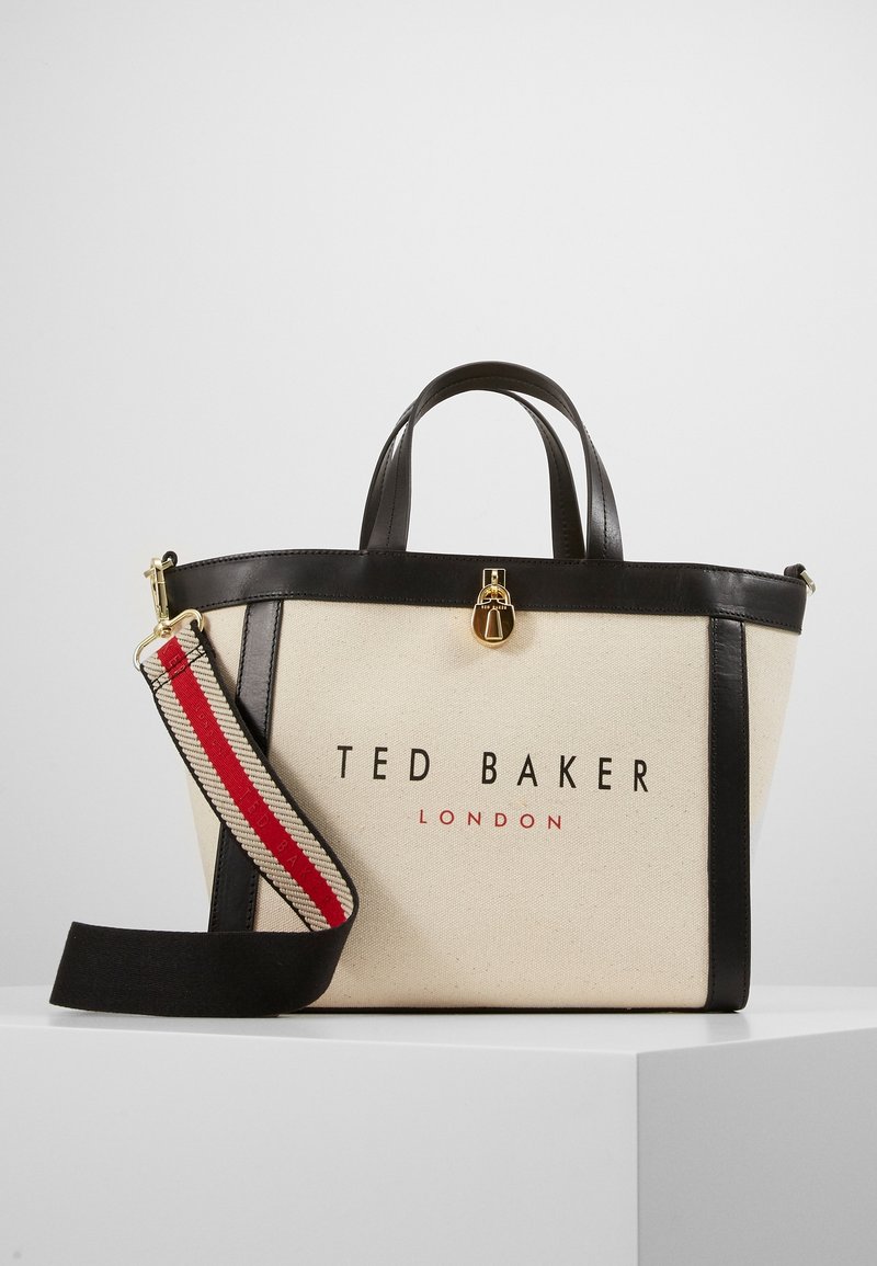 Sac cabas beige Ted Baker avec garniture en cuir noir, fermoir doré et bandoulière amovible rayée rouge, beige et noire.