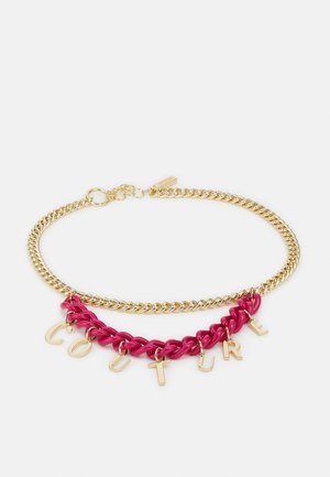 Gold chain necklace with a shorter pink chain; gold letter charms spelling "COUTURE" hang from the pink chain.