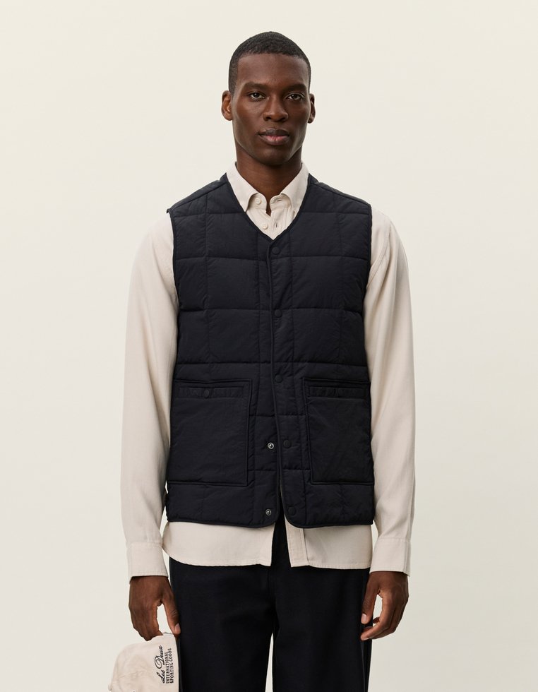 Πολυθρόνα ναυτικού τύπου με πλισέ σχέδιο, με δύο μπροστινές τσέπες και κουμπιά snap, φορεμένη πάνω από ένα ανοιχτόχρωμο πουκάμισο.