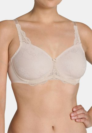 Beige lace bra with adjustable transparent straps, featuring floral pattern detail and a small satin bow at the center, soft texture.