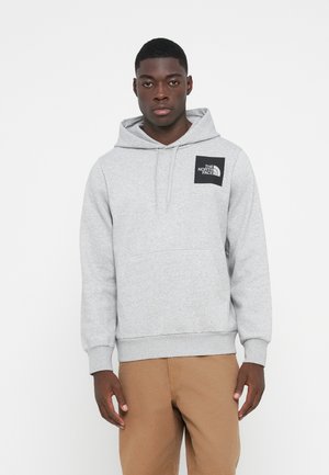 Pullover hoodie i klart gråt fleece med en stor forlommer og ribbede håndled. Har et sort logo patch på venstre bryst.