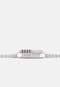 Relógio digital prateado com mostrador retangular, botões pretos, realces vermelhos e uma pulseira flexível em metal cinza. Design compacto e minimalista.