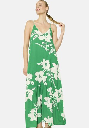 Robe maxi verte avec un motif floral blanc, décolleté en V et bretelles spaghetti ; possède une jupe à volants et un tissu léger.