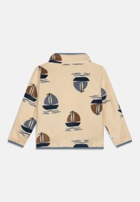 Lichtbeige fleece pullover met een bootafdruk in bruin, marineblauw en blauw. Het heeft een opstaande kraag en gebreide mouwen.