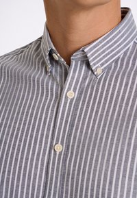 Button-down shirt in blue and white stripes, featuring a classic collar and small, rounded buttons. Material appears smooth with a textured finish.