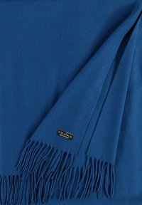 Écharpe en laine bleue avec des bords à franges. Texture douce et couleur unie. Étiquette de marque avec logo visible dans un coin.