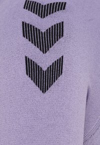 Lila tyg med tre svarta zigzag-linjer och vertikala linjer som skapar en texturerad kontrast mot en slät bakgrund.
