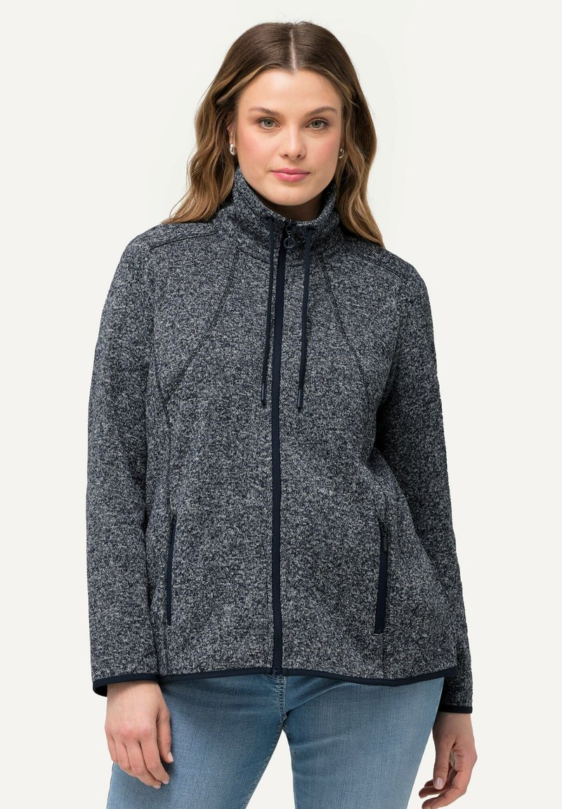 Mörkblå zip-up jacka med hög krage, utrustad med texturerat tyg, två sidofickor och kontrasterande marina accentfärger vid dragkedjan och nederkanten.