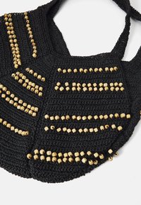 Μαύρη πλεκτή τσάντα που διαθέτει σχέδια από μικρές, ανοιχτόχρωμες ξύλινες χάντρες σε όλη την επιφάνεια, με δύο ανθεκτικούς ιμάντες ώμου.