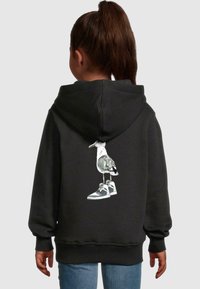 Czarna bluza z kapturem z grafiką ptaka stojącego na sneakersach z tyłu. Miękka tkanina, luźny krój oraz ściągacze przy mankietach i dolnym końcu.