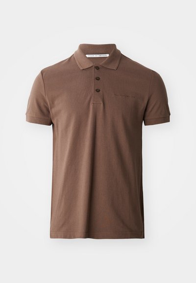 Καφέ πόλο μπλούζα φτιαγμένη από βαμβάκι με κλασικό γιακά, τρία κουμπιά και κοντά μανίκια. Έχει το λογότυπο κεντημένο στο στήθος.