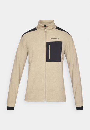 Beige fleecejakke med svarte skulderdetaljer og en frontlomme. Har høy krage og glidelåslukking. Teksturet stoff.