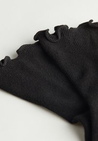 Sorte rynkede ankelsokker med ribbet tekstur, der har en bølget kant foroven og en glat finish på kroppen.