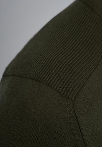 Dunkelgrüner Strickpullover mit einem gerippten Textur am Schulterbereich, glattem Stoff darunter und sauberen Nähdetails.