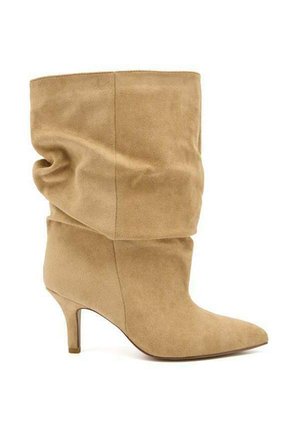 Botte souple en daim beige mi-mollet avec bout pointu et talon fin de hauteur moyenne, vue de côté sur fond blanc uni.