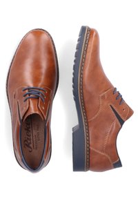 Scarpe in pelle marrone con una finitura liscia, punta rotonda e lacci blu. Presentano un pannello laterale testurizzato e una suola robusta e decorata.