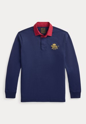 Polo à manches longues bleu marine avec un col rouge, un logo lion brodé en or et une patte de boutonnage à trois boutons. Matière en coton doux.