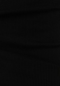 Tissu noir côtelé avec une texture douce, présentant des lignes verticales pour plus de profondeur et de dimension. Convient à diverses applications vestimentaires.