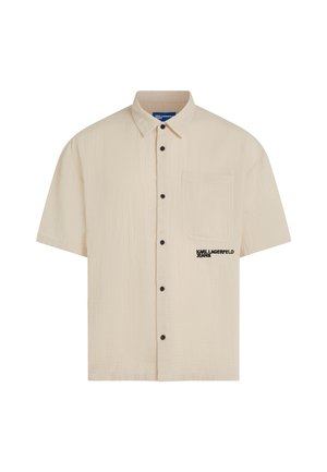 Beige kortermet skjorte med knapper, krage, brystlomme, svarte knapper og "Karl Lagerfeld Jeans"-logo på lommen.