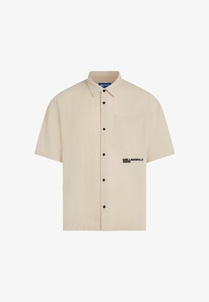 Beige kortermet skjorte med knapper, krage, brystlomme, svarte knapper og "Karl Lagerfeld Jeans"-logo på lommen.