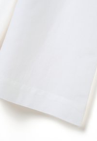 Witte linnen stof met een gladde textuur, subtiele natuurlijke vezels en een schone, rechte zoom. Geen zichtbare patronen of hardware.