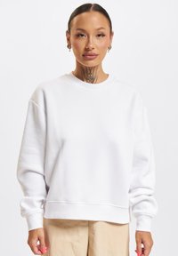 Weißes Sweatshirt mit Rundhalsausschnitt, versetzten Schultern und gerippten Bündchen. Weicher Stoff mit lockerer Passform, der eine glatte Textur aufweist.
