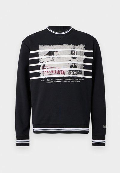 Sweat-shirt noir à col rond avec des rayures blanches sur le col, les poignets et l'ourlet, arborant un personnage de dessin animé usé et le texte "BUSTED".