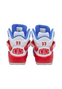 Sneaker bianche con accenti rossi e blu, dotate di un colletto blu imbottito, branding "EWING" e fasce in Velcro. Il numero "33" è visibile sul retro.